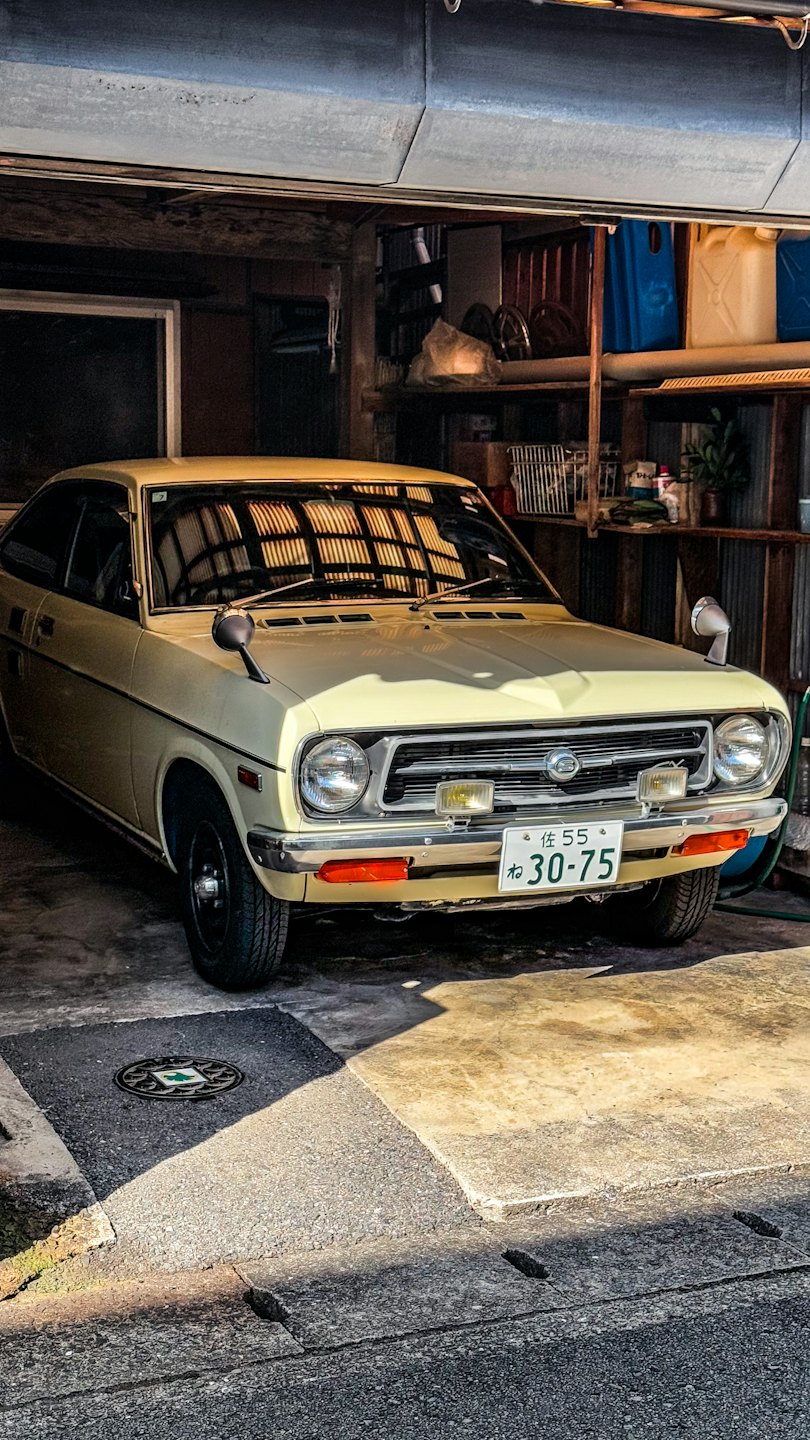 Ein Oldtimer-Auto in Gelb, das in einer rustikalen Garage parkt.
